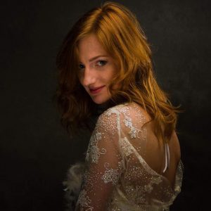 Professionele fotograaf die een vrouw vastlegt tijdens een fotosessie in een industriële omgeving.